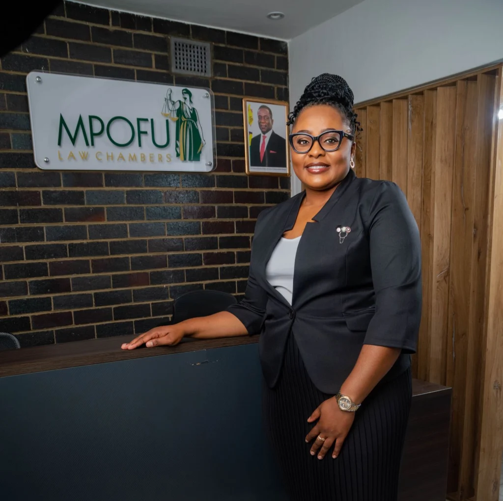 Dudzai Annah Mpofu at the reception, in front of the firm’s logo wall